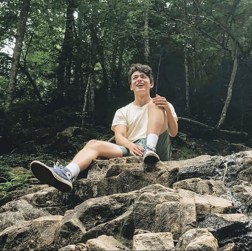 Jordan sitting on a rock in a forest